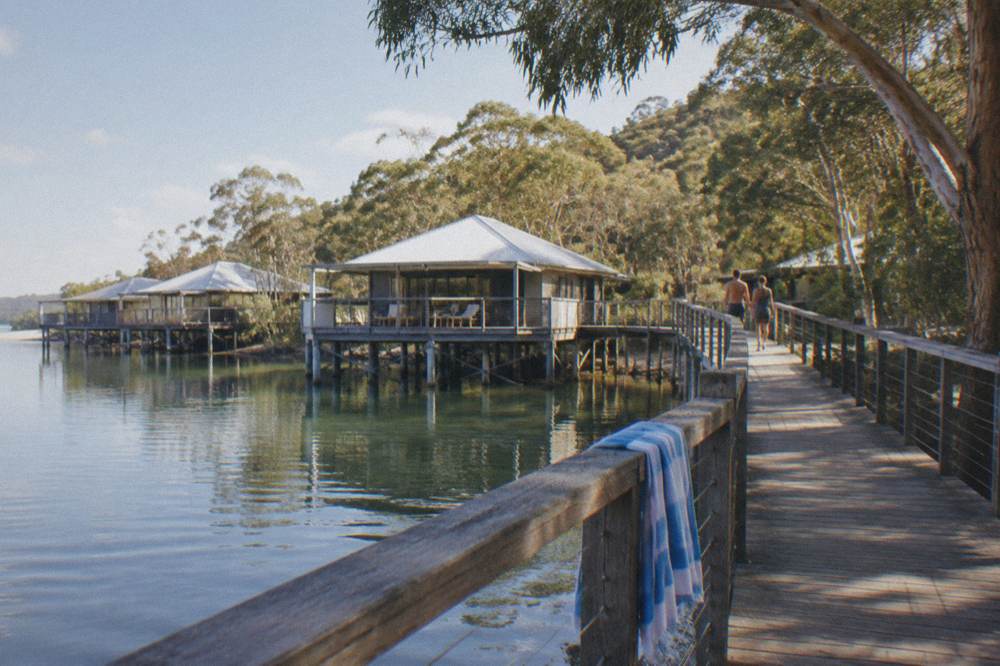 Wooden boardwalk leading to resort villas beside calm strait water