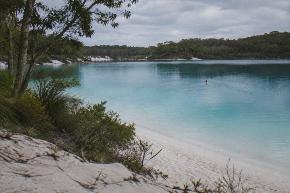 A turquoise freshwater lake ringed by white sand and forest