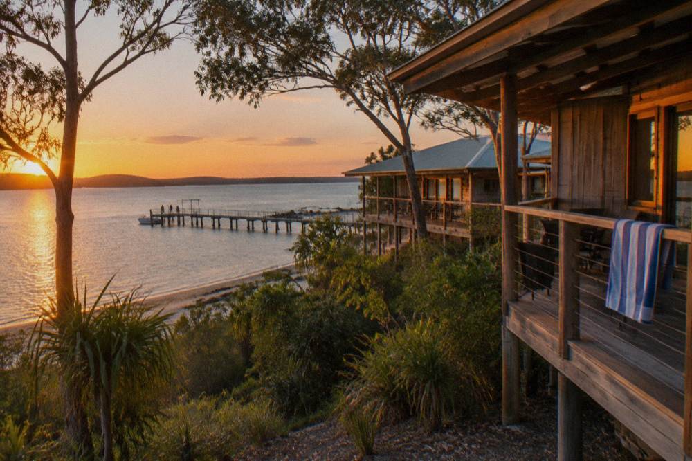 A timber resort building beside a beach at sunset