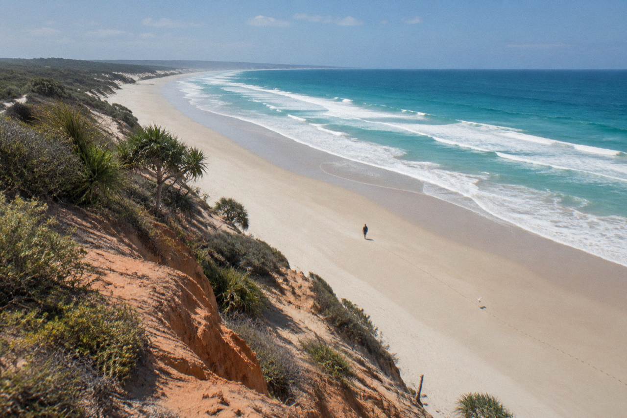 Long empty ocean beach on K'gari with sand cliffs and clear blue water