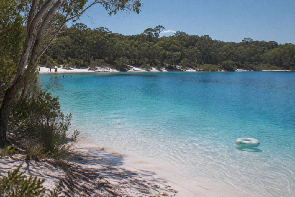 A turquoise freshwater lake ringed by white sand and forest on a sand island