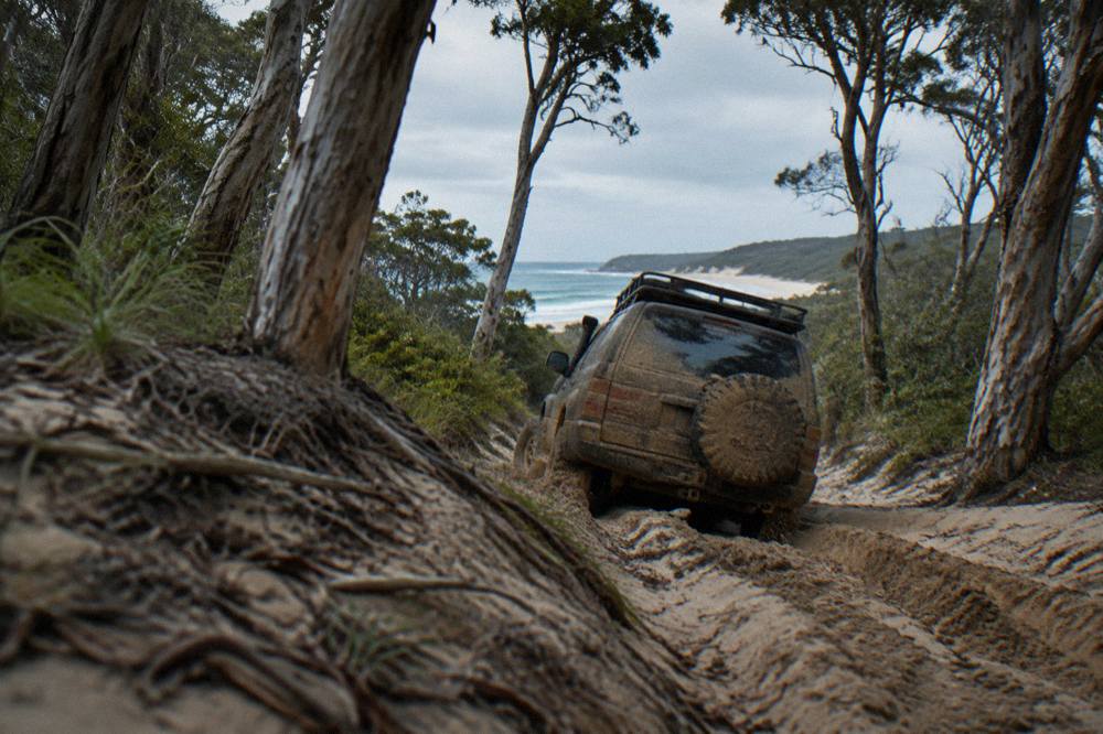 A four wheel drive vehicle on a soft sandy inland track through coastal forest