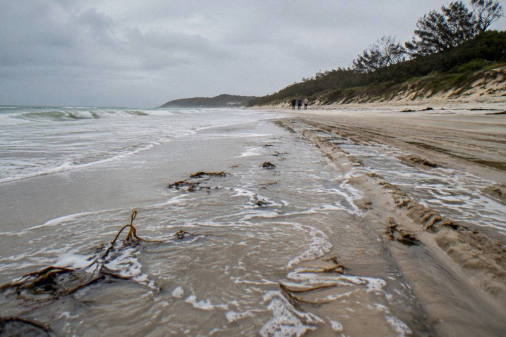 Waves reaching high on a wide sand beach at rising tide with soft sand above the waterline