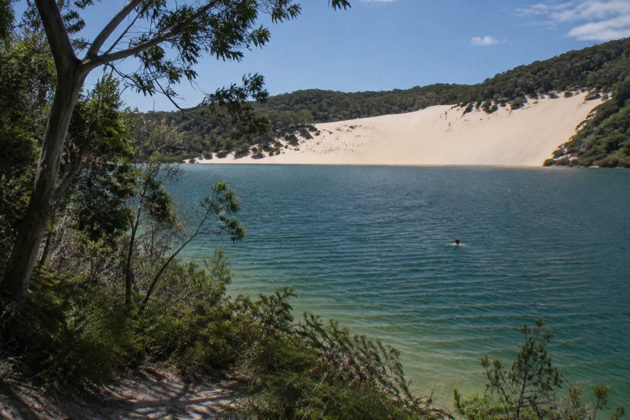 Clear blue freshwater lake ringed by white sand and forest on a sand island