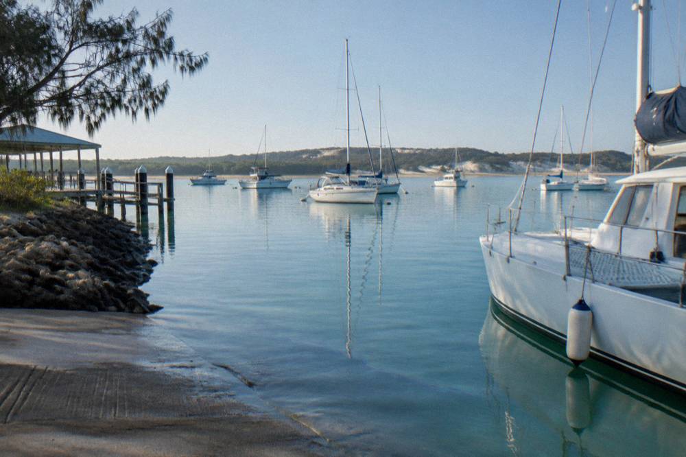 Calm turquoise bay water under a clear sky with boats at anchor