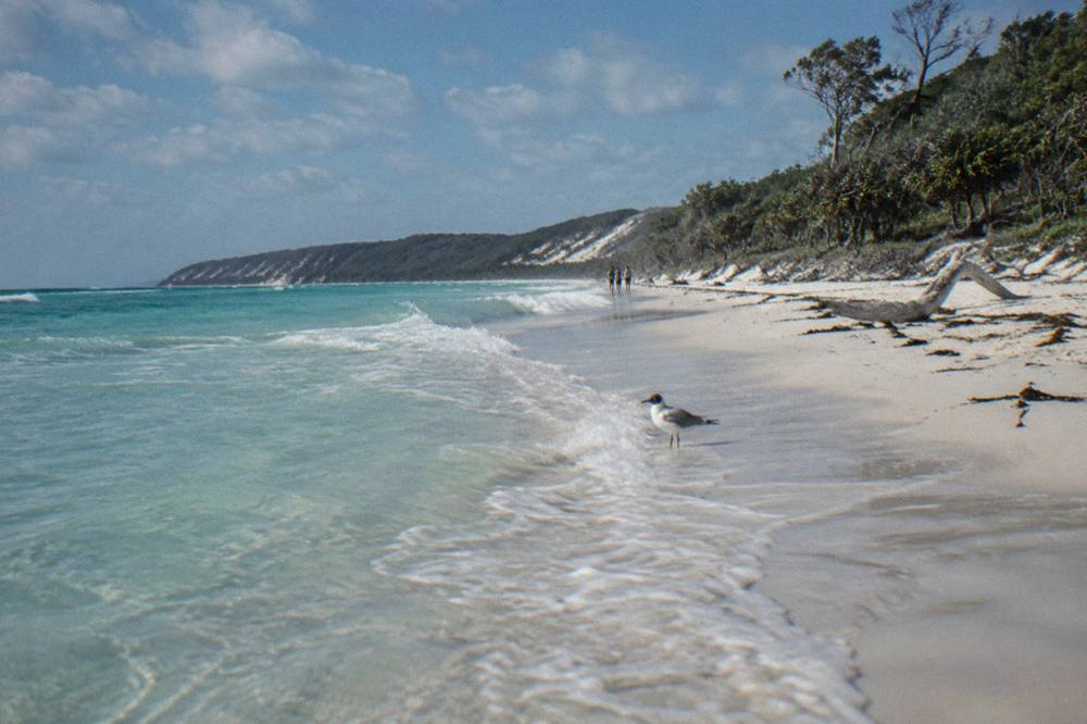 White sand beach and clear turquoise water under scattered clouds