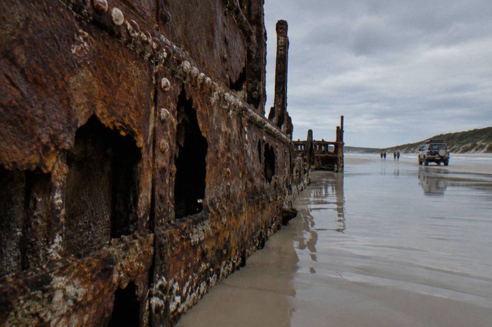 A four wheel drive tour vehicle travelling along a firm sand beach at low tide