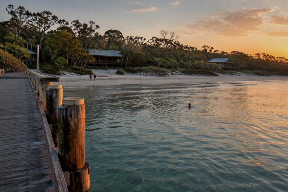 Wooden jetty over clear water at a resort beach at sunset