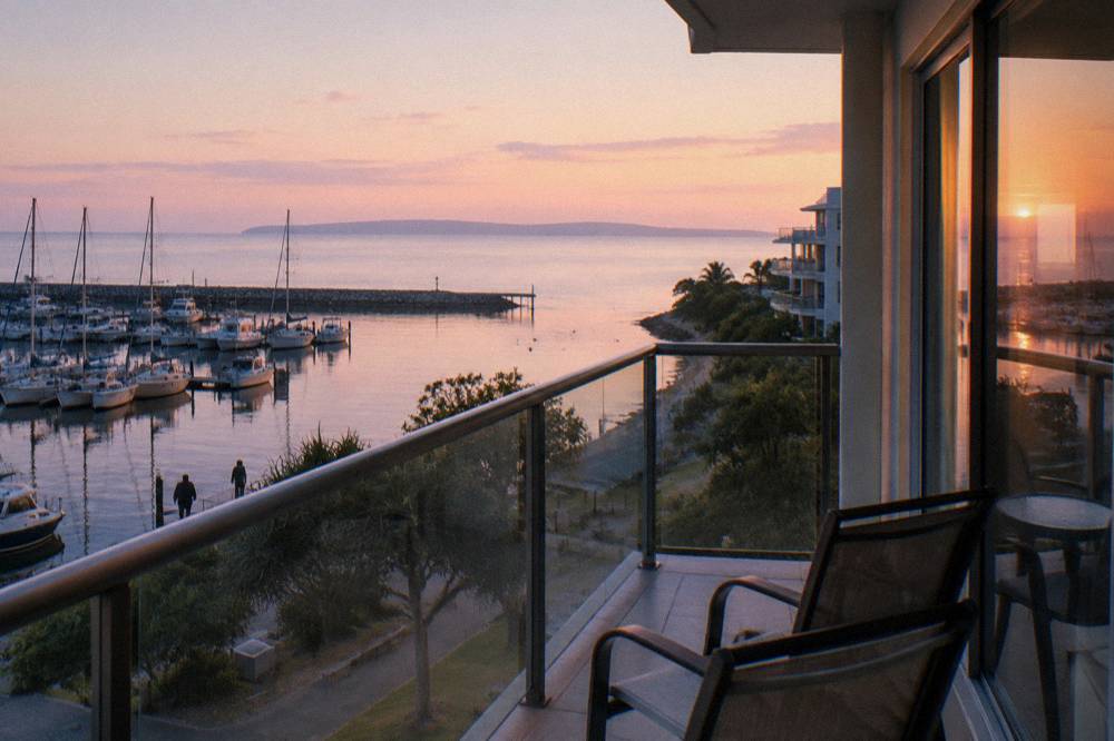 Apartment balconies overlooking a calm mainland bay at dawn
