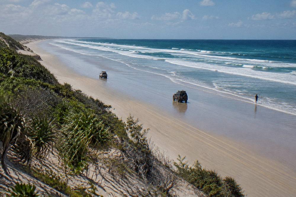 Four wheel drive vehicles travelling along a wide firm sand beach at low tide