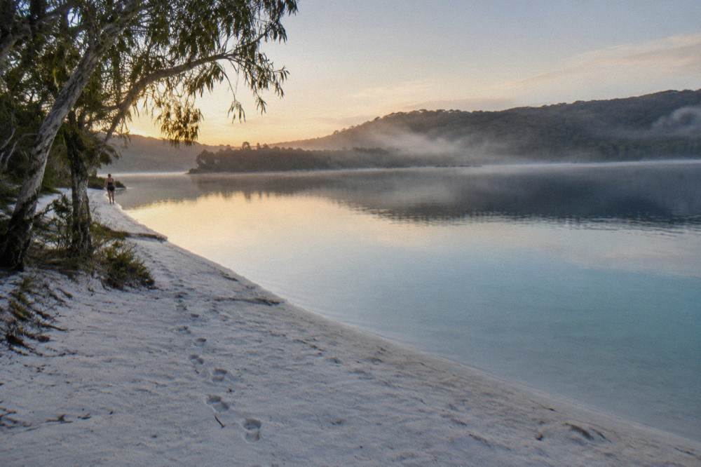 Morning light over a calm freshwater lake edged by pale sand