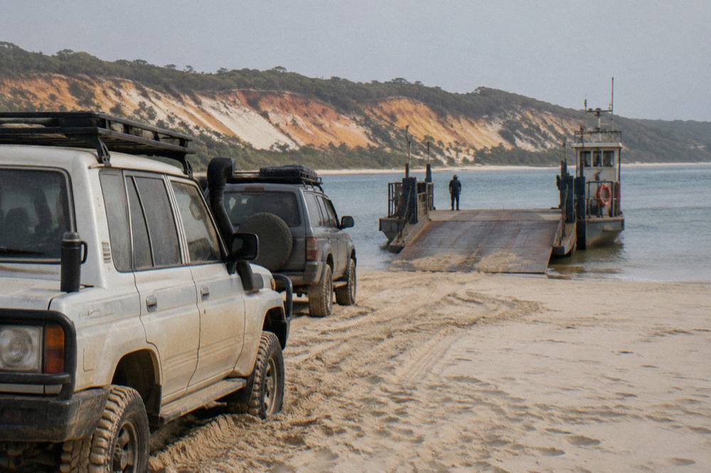 A four wheel drive vehicle queueing on soft sand at a beach barge ramp waiting to board