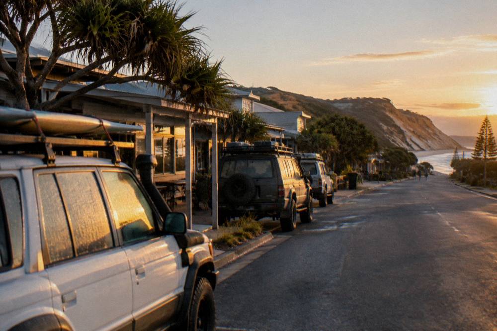 A coastal town main street at sunrise with touring vehicles parked and ready for departure
