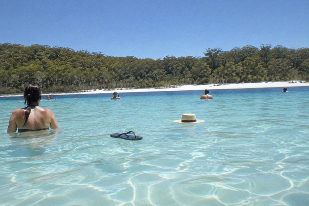 A turquoise freshwater lake ringed by white sand and forest on a sand island