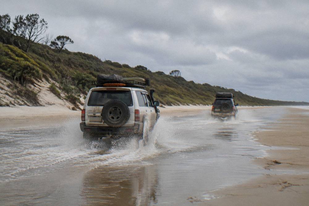 Four wheel drive vehicles travelling along a firm sand beach at low tide
