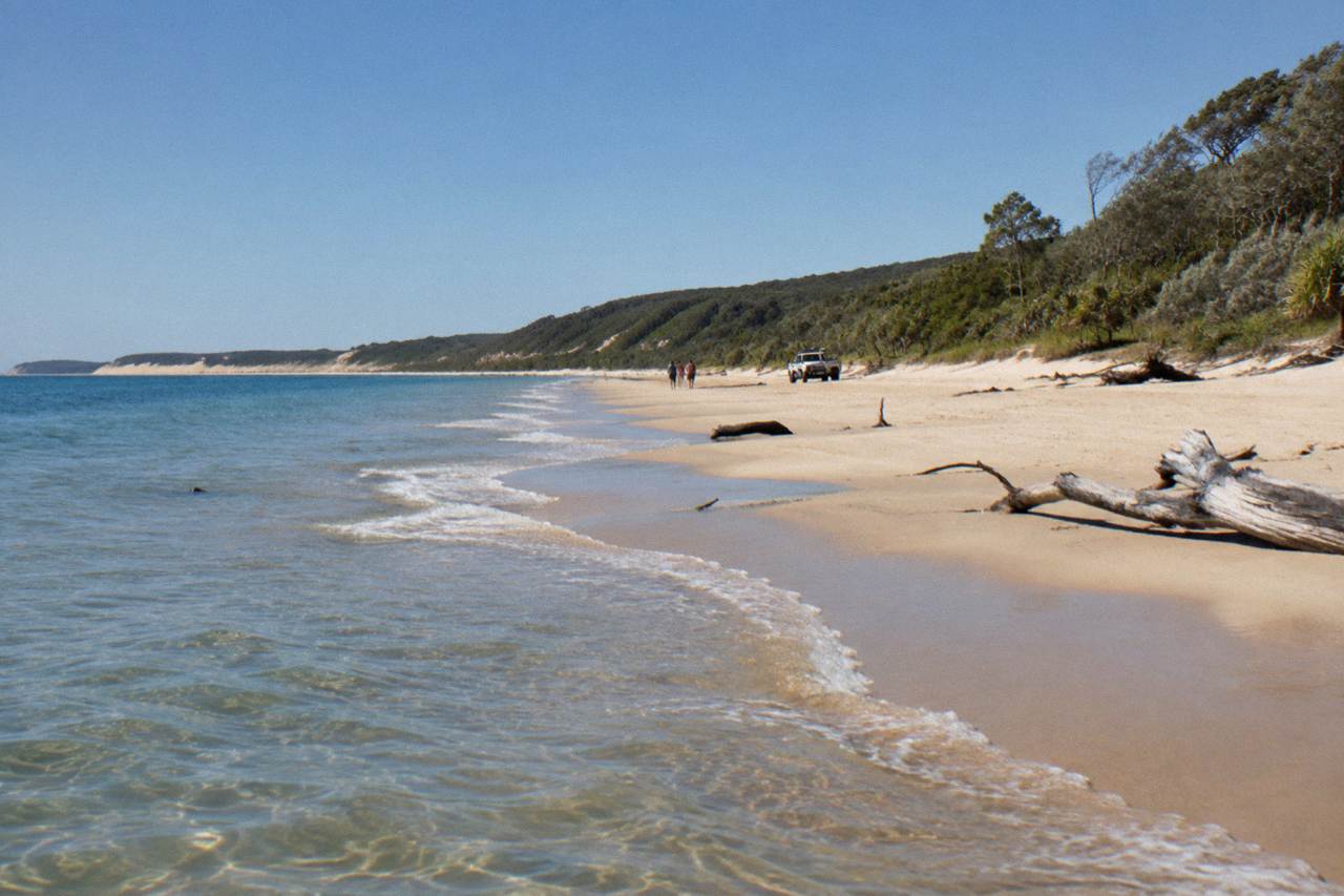 Wide sandy beach along a large sand island with calm blue water and clear sky